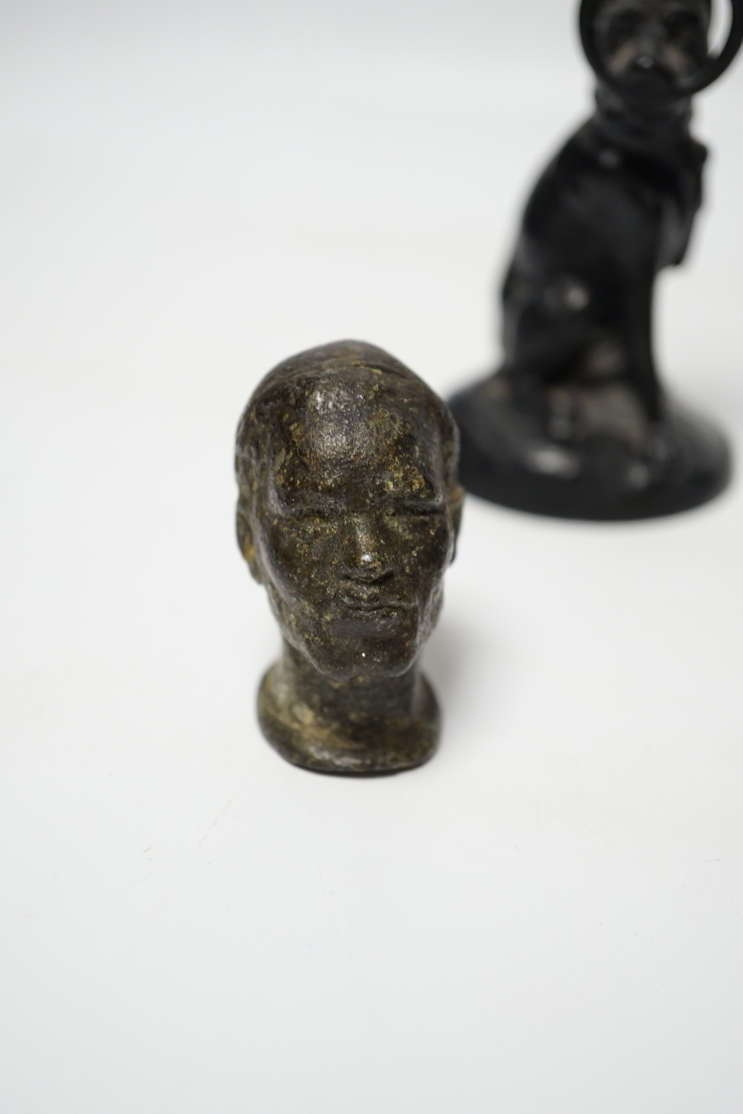 A Victorian brass hand paper clip, a small bronze tribal head and novelty dog candlestick, tallest 15cm high